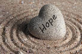 heart shaped rock in sand with word hope 